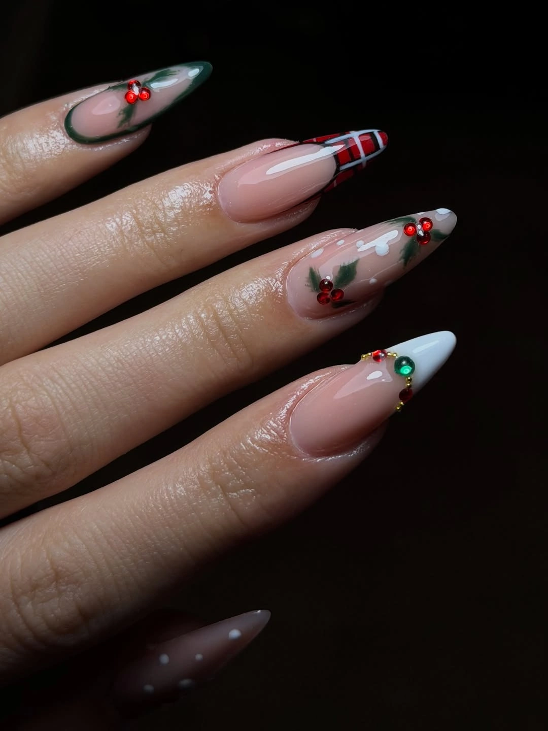 Pointed nude nails with plaid, green tips, evergreen details, and reflective accents