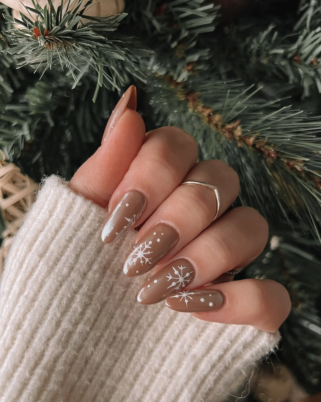 Almond taupe nails with white snowflakes, starbursts, and small dots