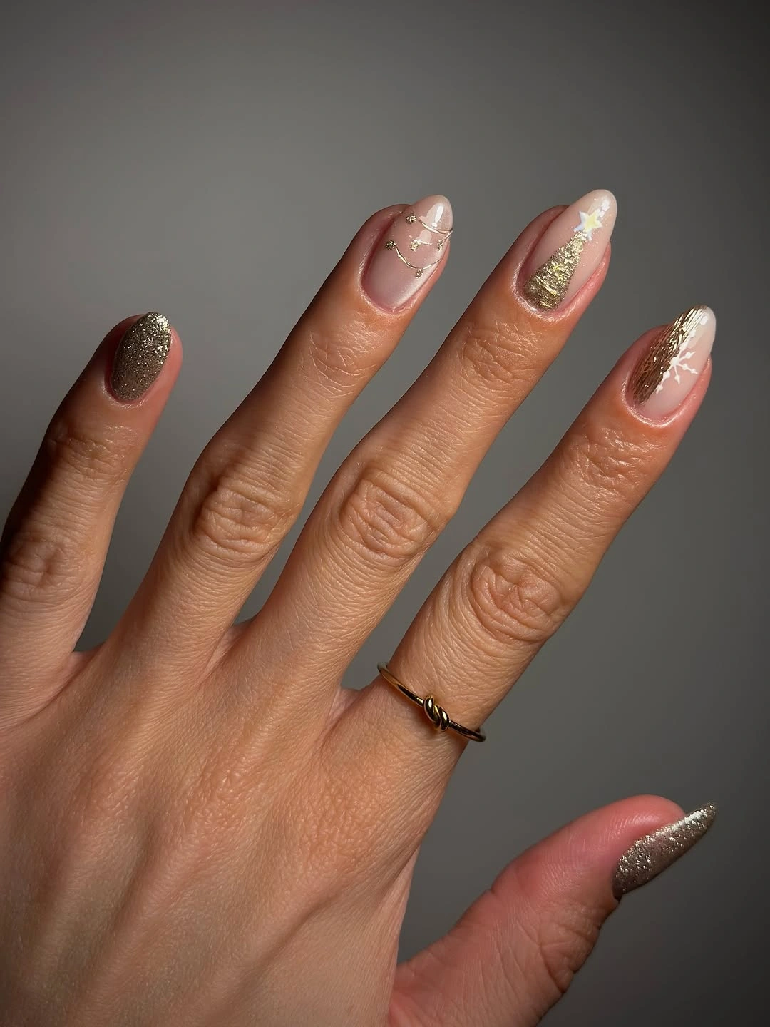 Almond nude nails with champagne glitter, gold tree, and delicate line details