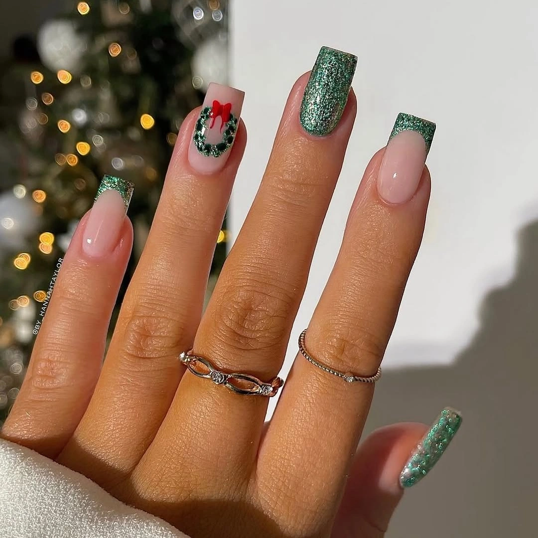 Long square nails with emerald glitter tips, wreath, and raised-looking red bow
