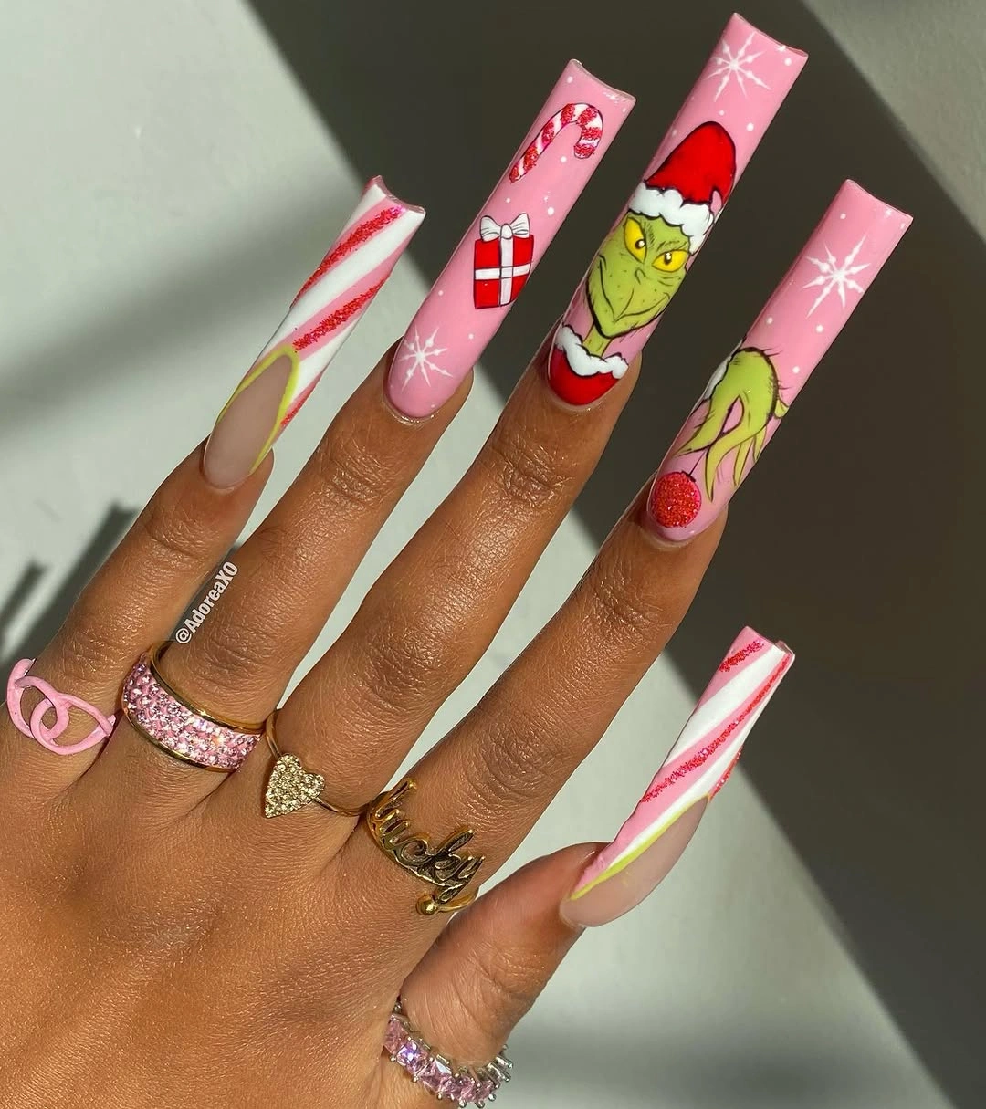 Extra-long square pink Grinch nails with candy canes and white starbursts