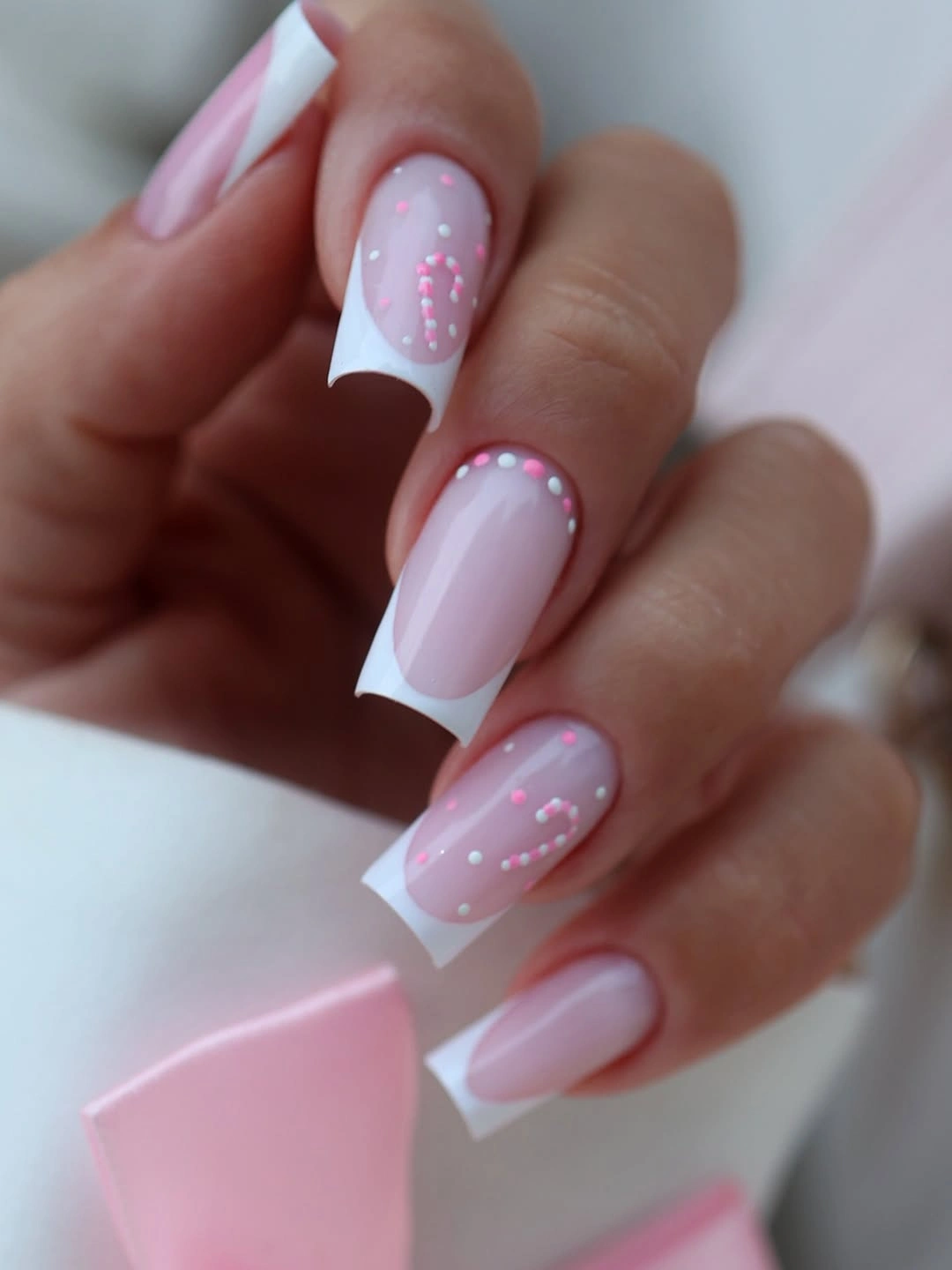 Long square pink French nails with white tips and tiny candy cane decorations