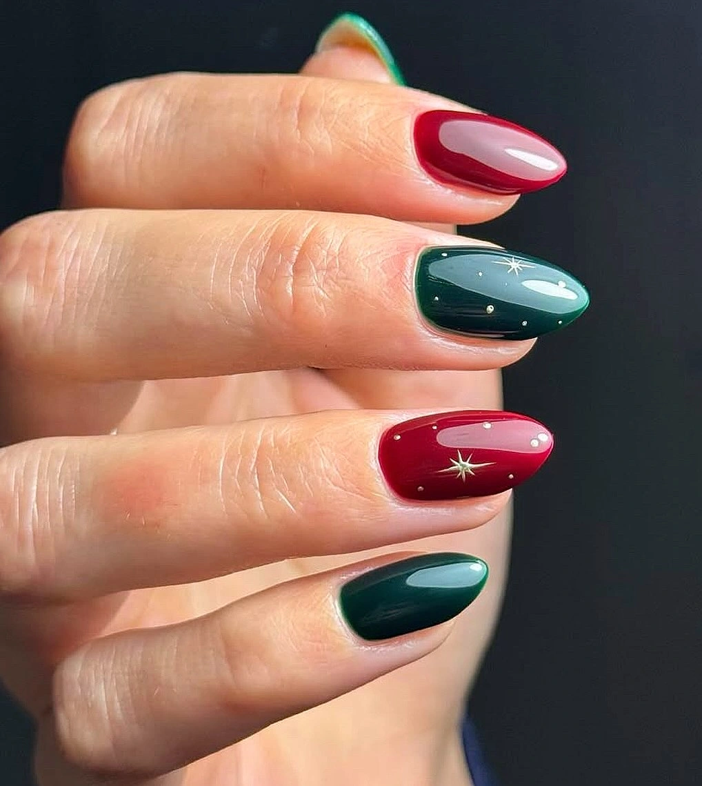 Short almond burgundy and forest green nails with tiny gold starbursts
