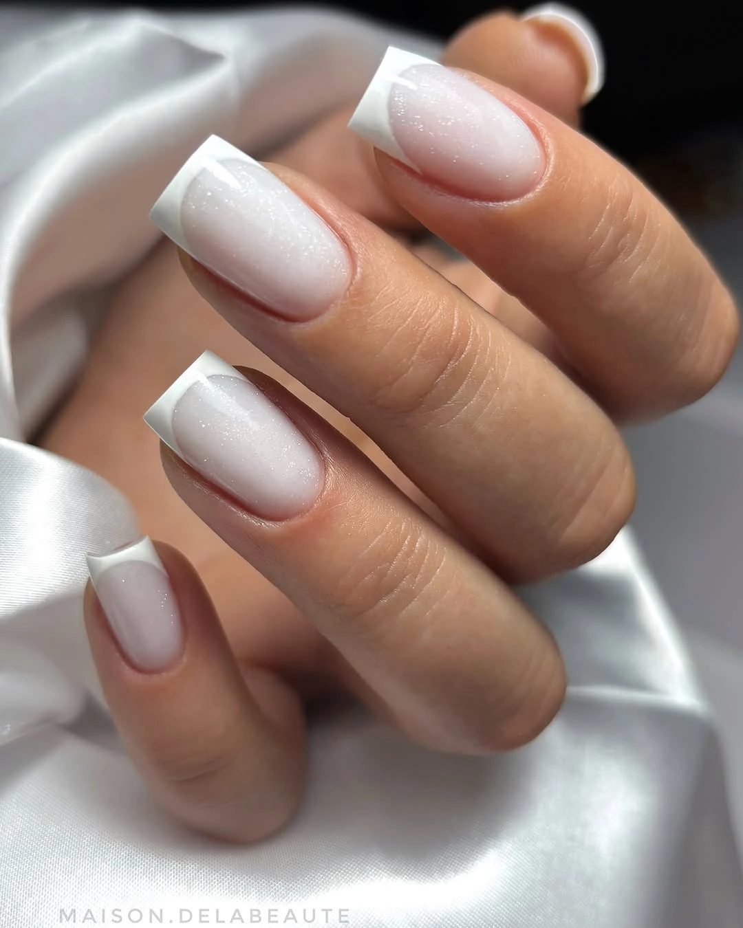 Short square nails with pearly milky bases and crisp white French tips