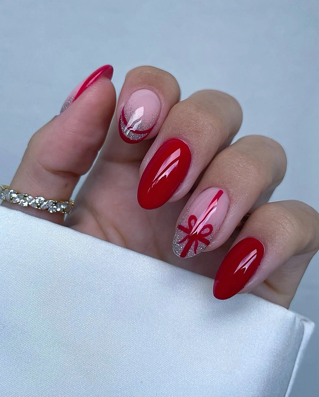Bright red almond nails with silver glitter French accents and red bow