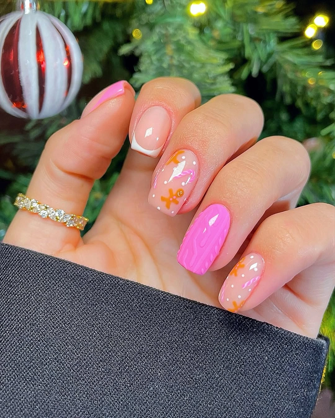 Short pink nails with miniature gingerbread figures and wavy bright pink accent