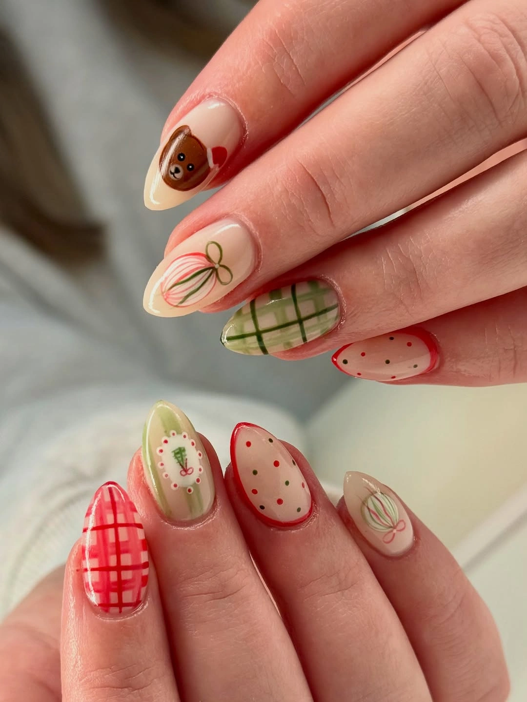 Short almond Christmas nails with red plaid green checks bows and festive illustrations