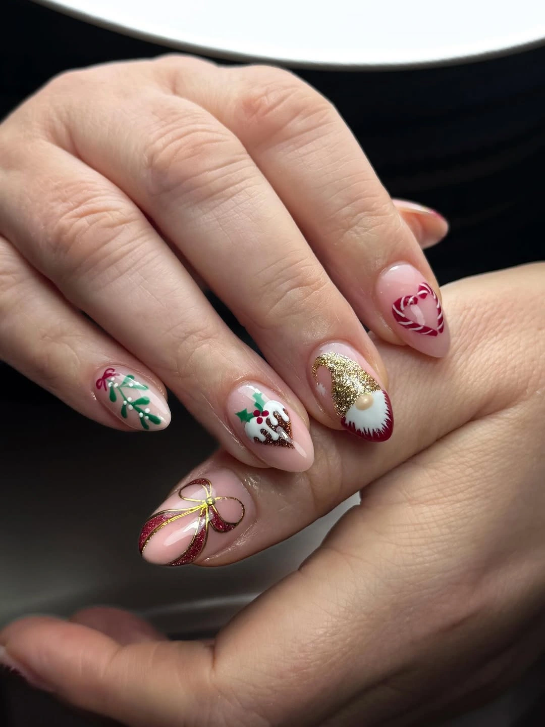 Sheer pink almond nails with green sprigs, red details and gold accents