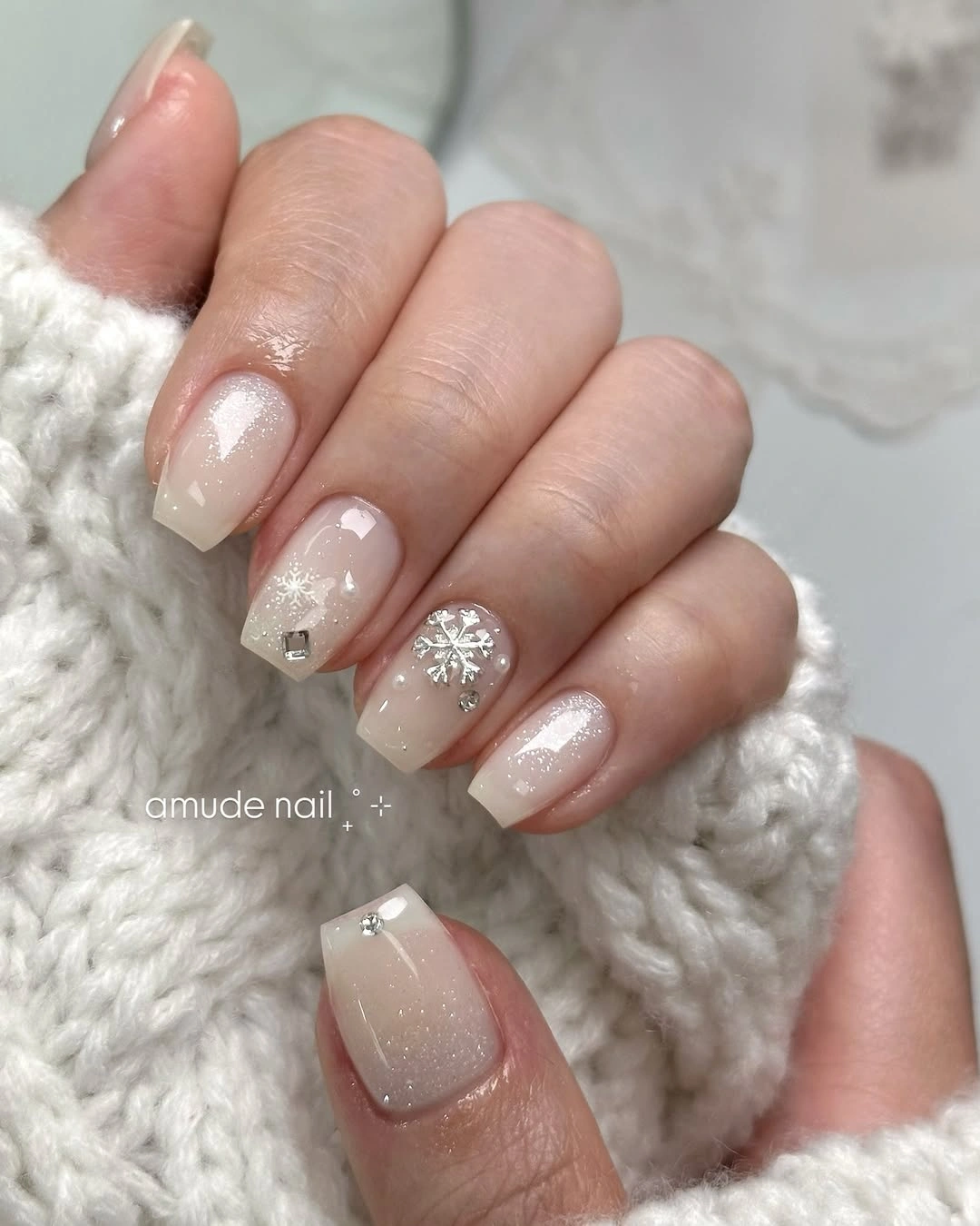 Short milky white square nails with shimmer and silver-toned snowflake accent