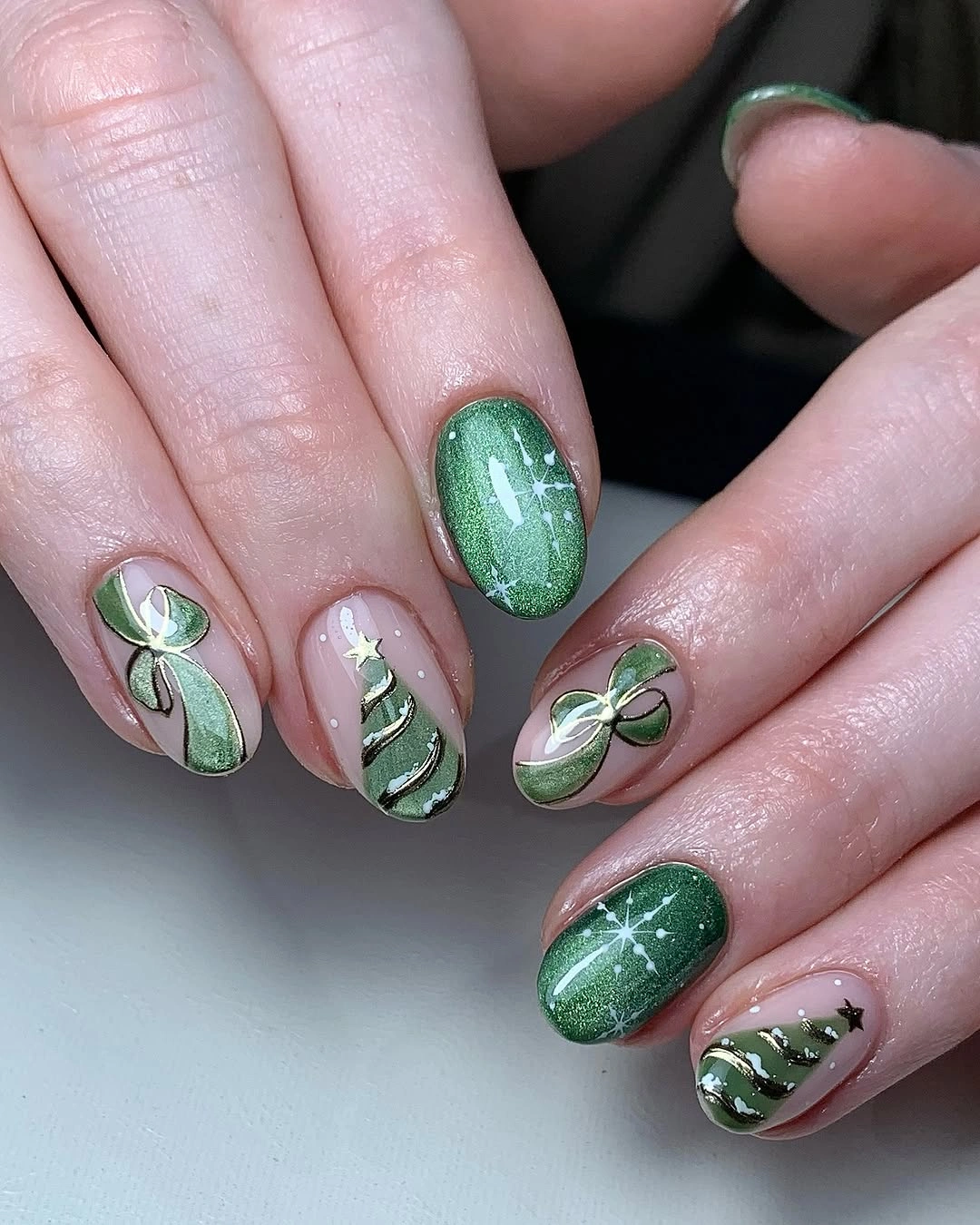 Short green shimmer nails with painted bows and miniature Christmas trees