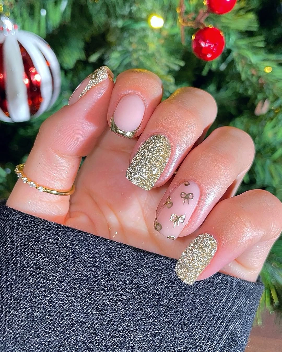 Short champagne gold glitter nails with blush pink bases and tiny bows