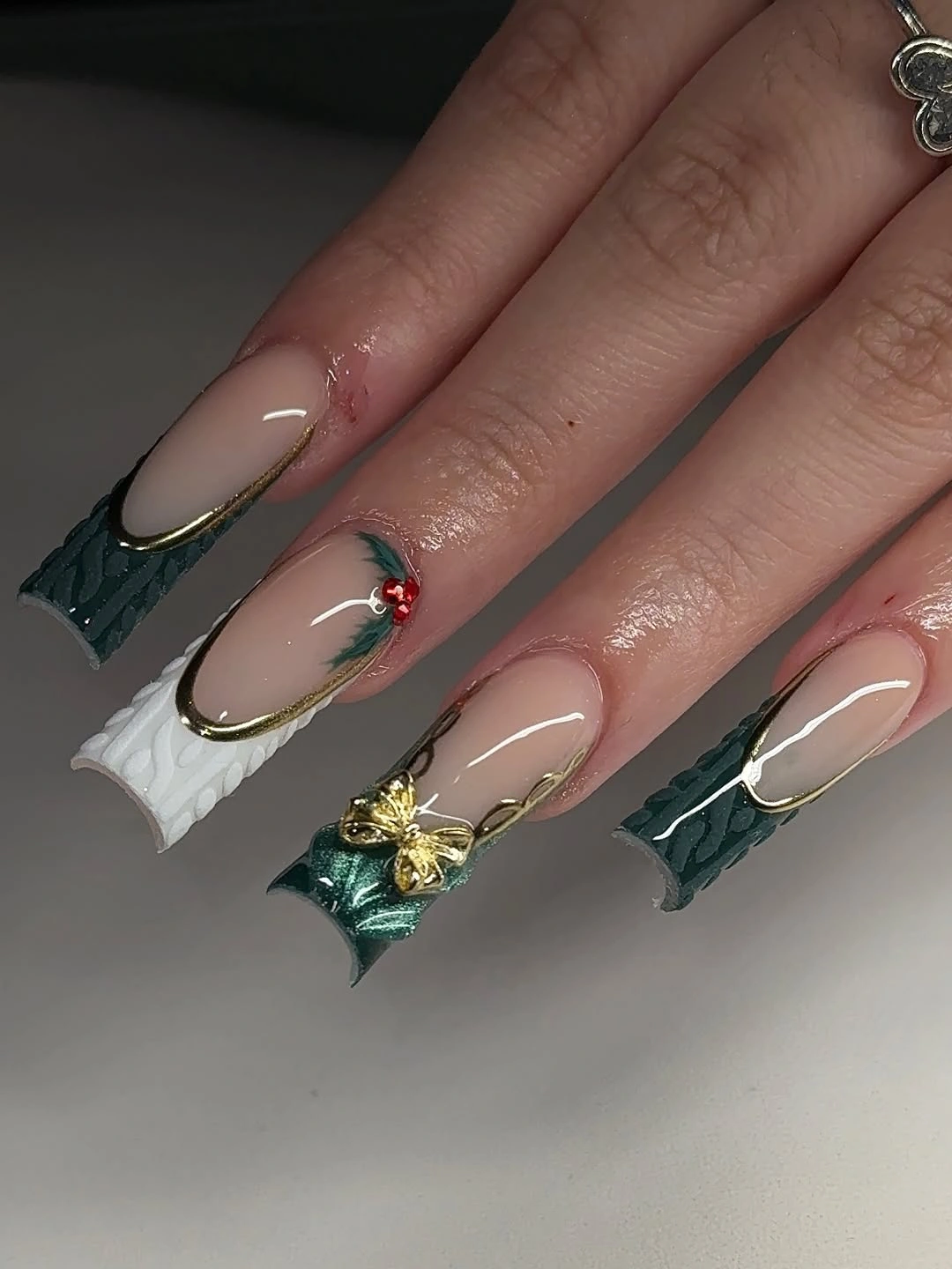 Extra-long square nails with textured emerald green tips and gold bow accents