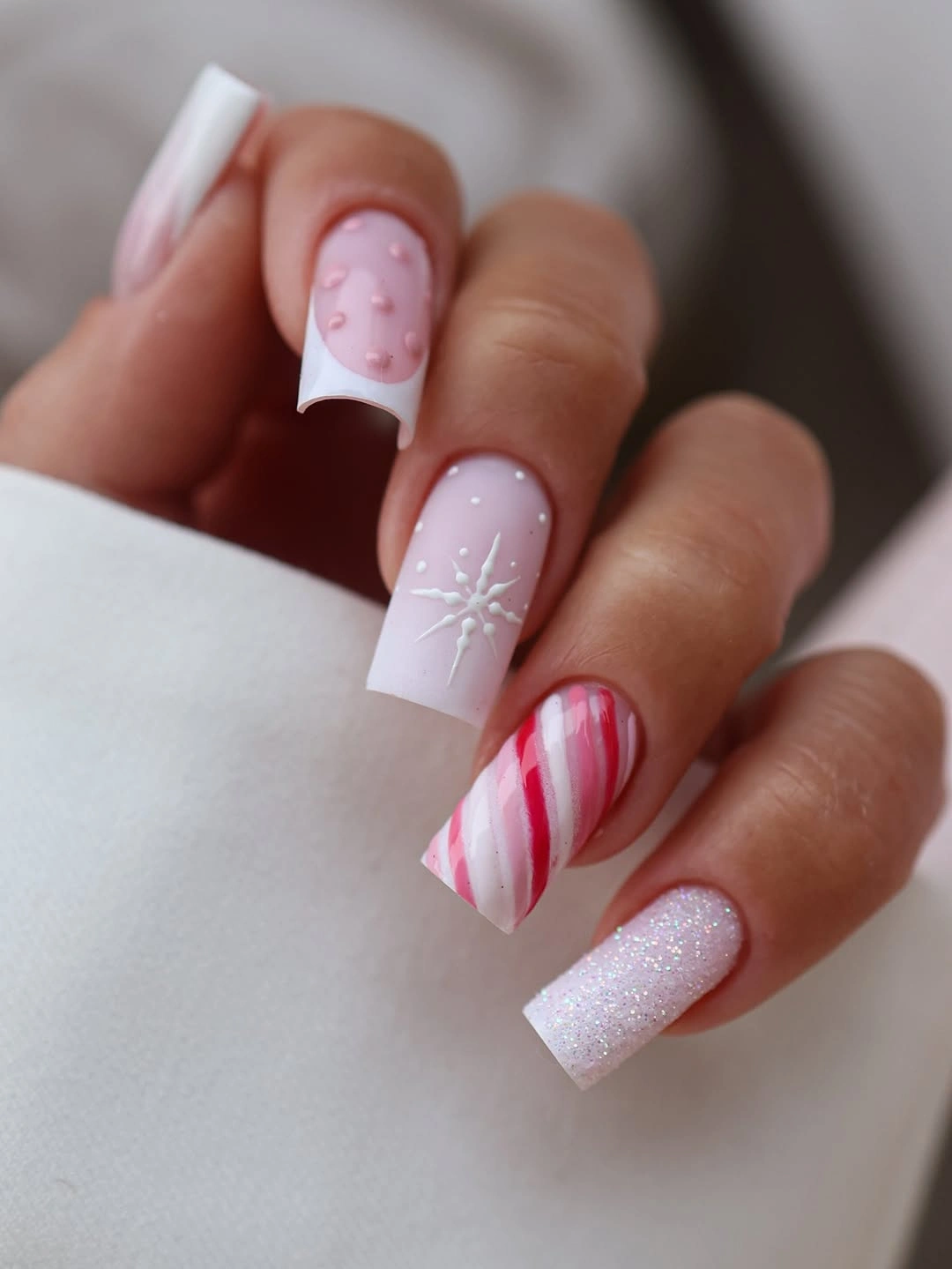 Long square pink nails with red candy cane stripes and white snowflake